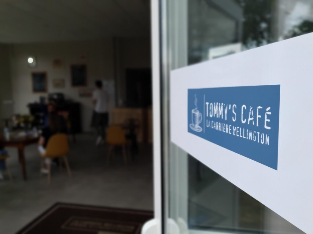 Logo indiquant "Tommy's Cafe La Carriere Wellington" sur la porte du batiment